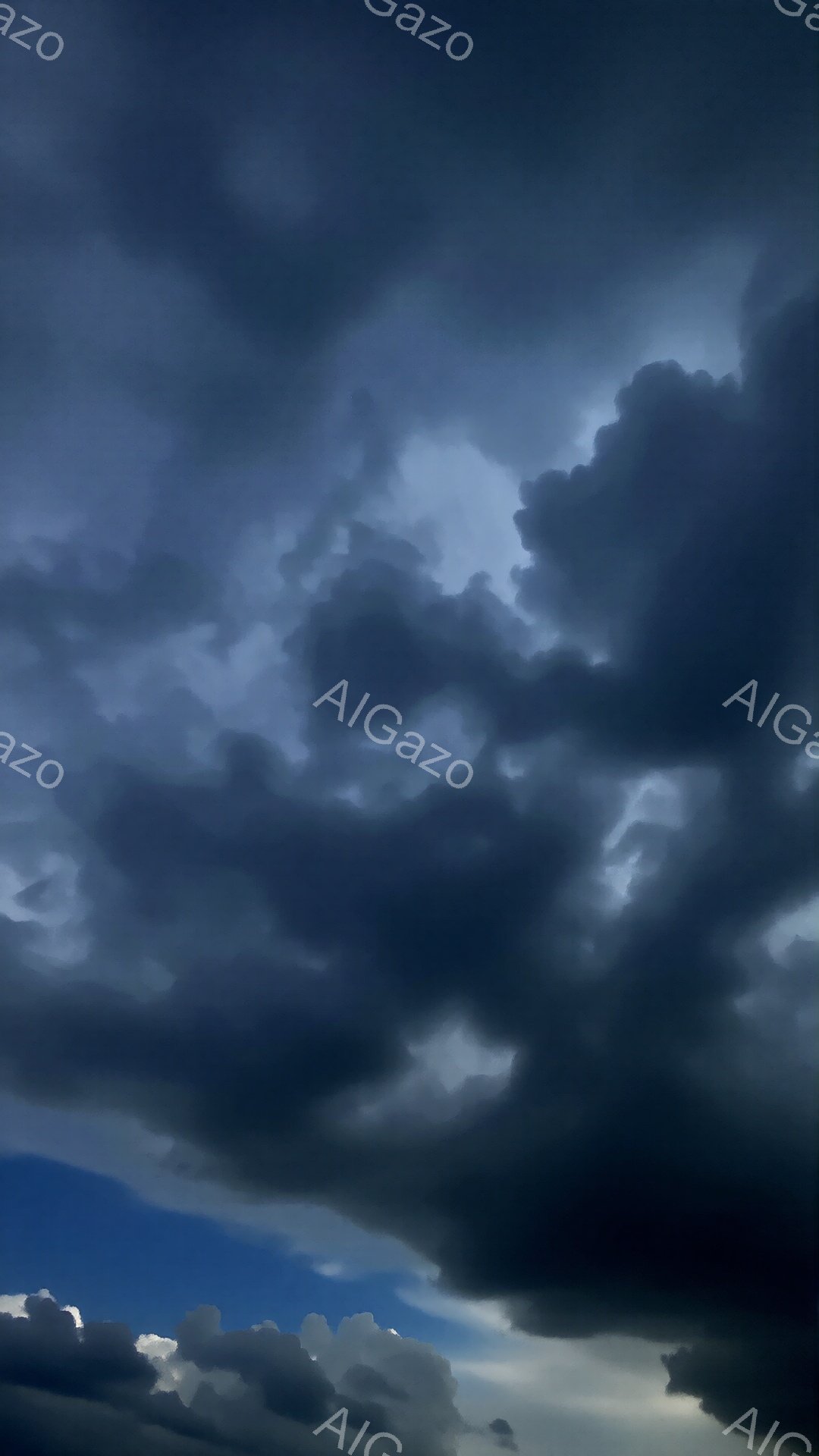 厚い暗雲が空を覆い、青い空が雲の隙間からわずかに覗いている。雲は重厚で、まるで嵐の前触れのような、ドラマチックな雰囲気を作り出している。全体的に、重苦しくも壮大な自然の力を感じさせる構図だ。