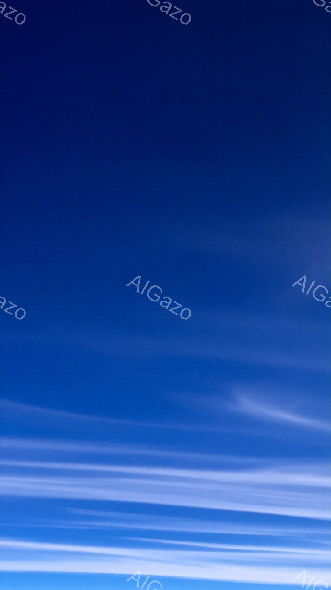 空全体が鮮やかな青色で覆われ、細い白い雲が水平方向に帯状に広がっています。雲は薄く、まるで筆で描かれたような繊細な線を描き、空の青さを際立たせています。この光景は、穏やかで静謐な、平和な雰囲気を醸し出しています。