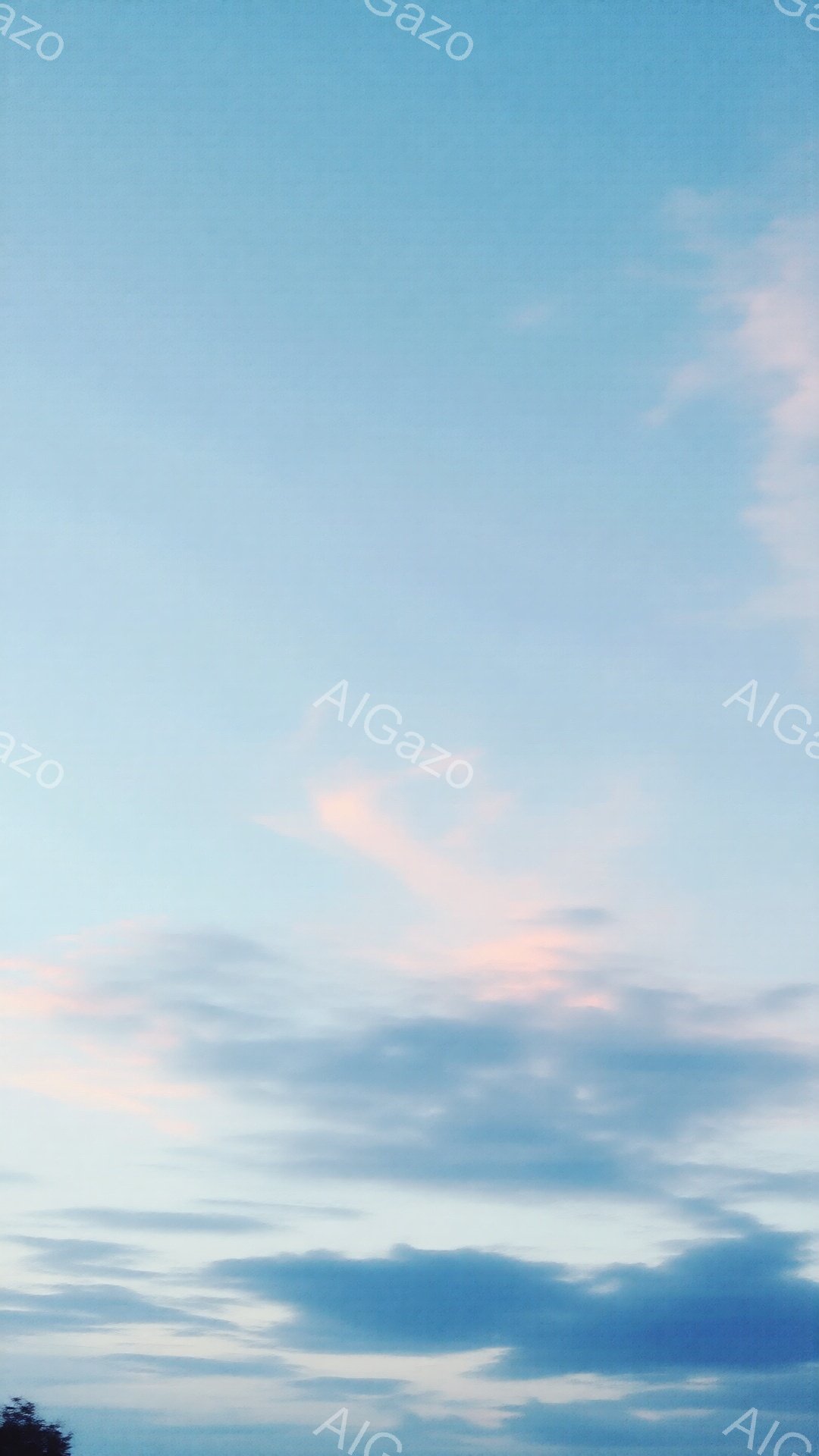 鮮やかな空には、淡いピンクと白の雲が広がっています。雲は層状になっており、夕焼けの名残が薄く感じられます。穏やかな雰囲気で、空全体が柔らかく包み込まれているようです。