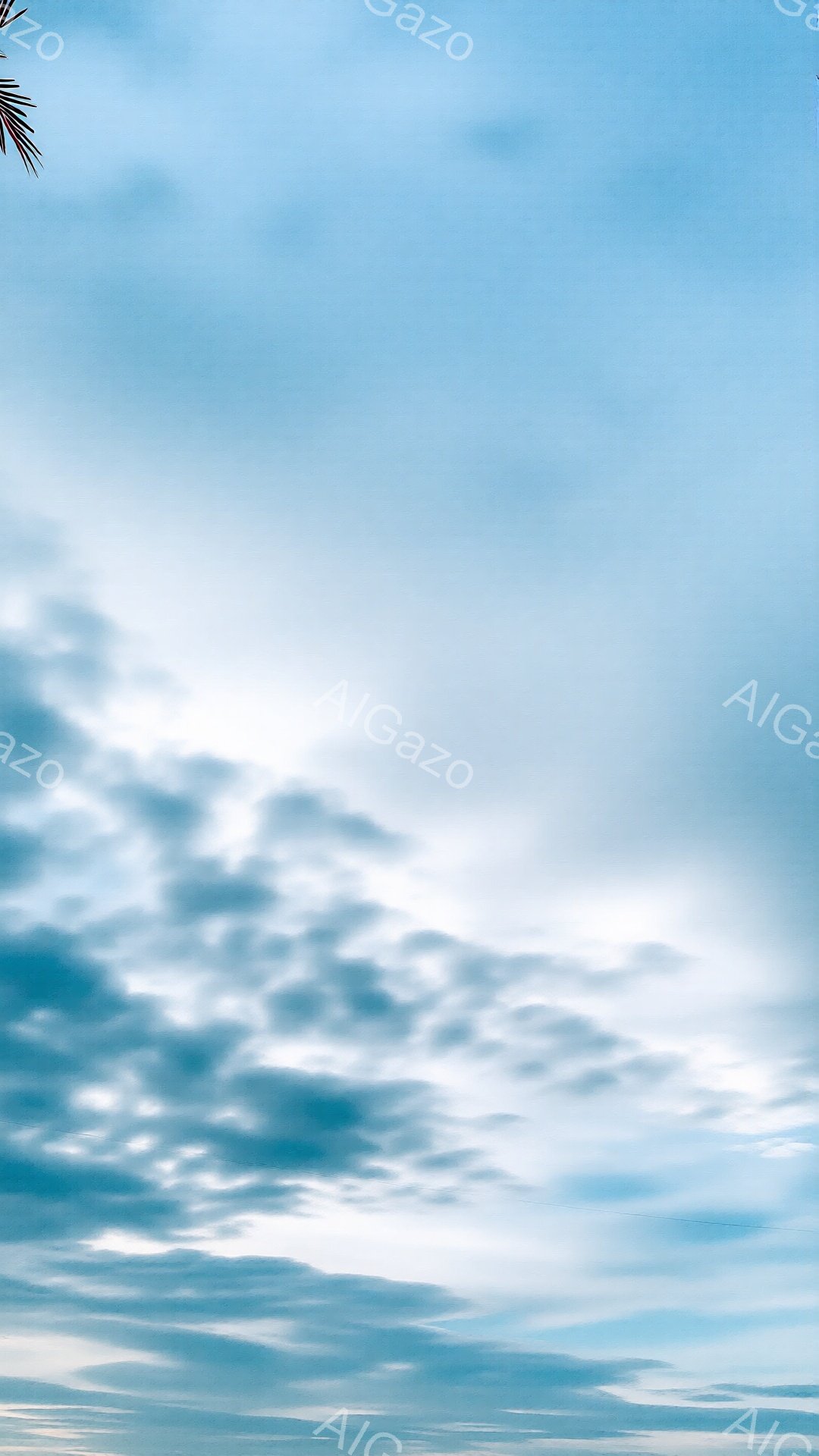 空は薄い青色から白へとグラデーションしており、ふわふわとした雲が広範囲に広がっています。雲はさまざまな形をしており、一部は明るい日差しに照らされ、他の雲は影を落としてコントラストを生み出しています。全体的に穏やかで晴れた日の空の風景です。