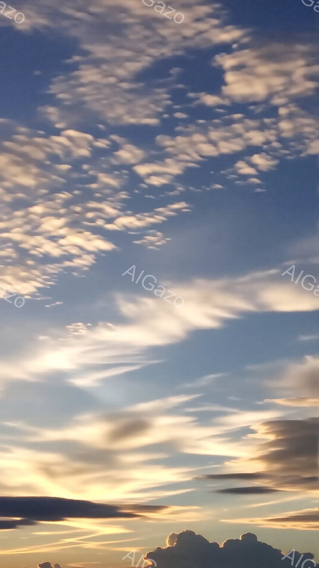 空は薄い水色から濃い青へとグラデーションを描き、所々に白い雲がふわふわと浮かんでいる。雲はまるで羊の群れのように、様々な形をしており、夕焼けの光を浴びて金色やピンク色に染まっている。穏やかで幻想的な雰 - AI生成フリー素材