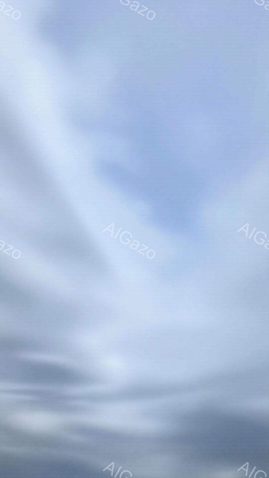 空全体が薄い雲に覆われ、明るい灰色と白が混ざり合っている。雲は横方向に伸びており、まるで海の波のようにも見える。全体的に穏やかで静かな雰囲気が漂い、静寂と平和を感じさせる。