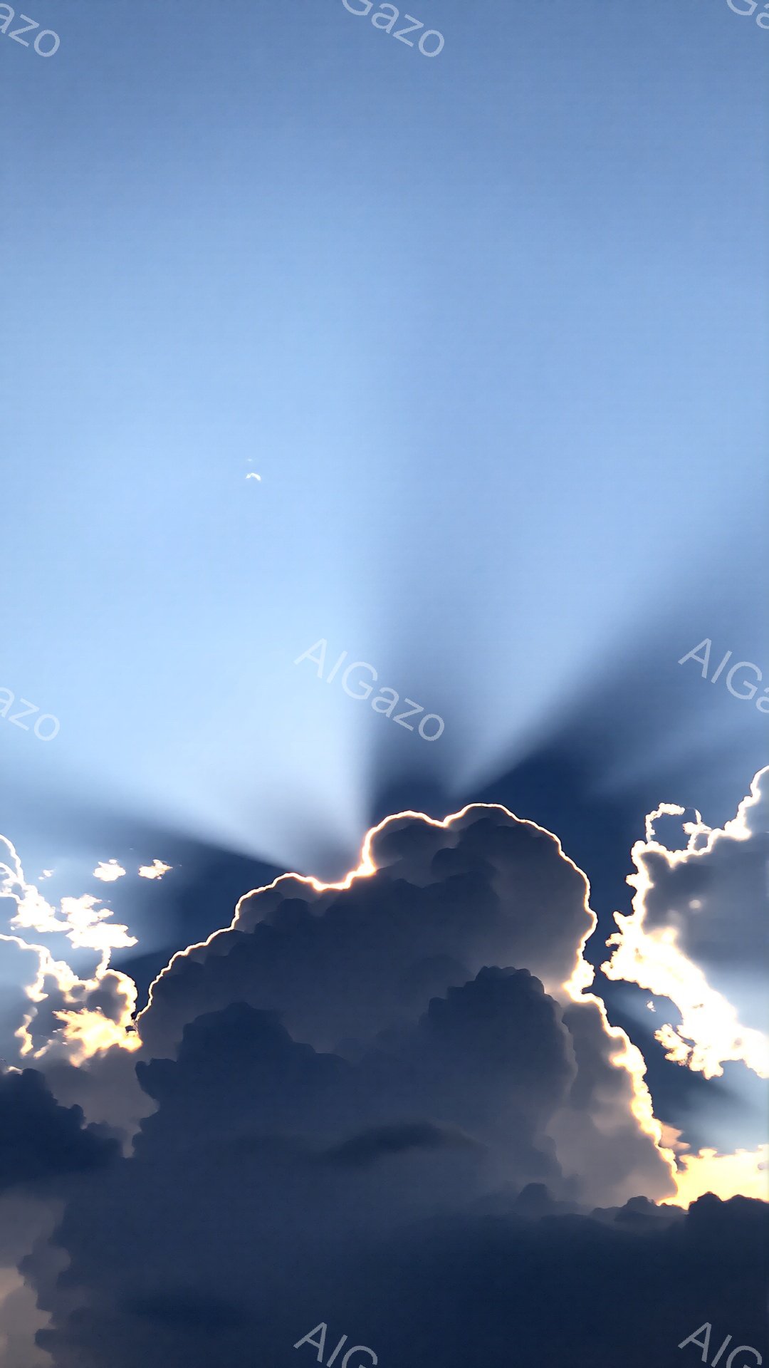 厚い暗雲が画面の中央に大きく広がっており、雲の端は太陽の光によって金色に縁取られています。雲の隙間から差し込む光線が放射状に広がっており、ドラマチックな雰囲気を生み出しています。背景は明るい青空で、雲のコントラストが際立っています。