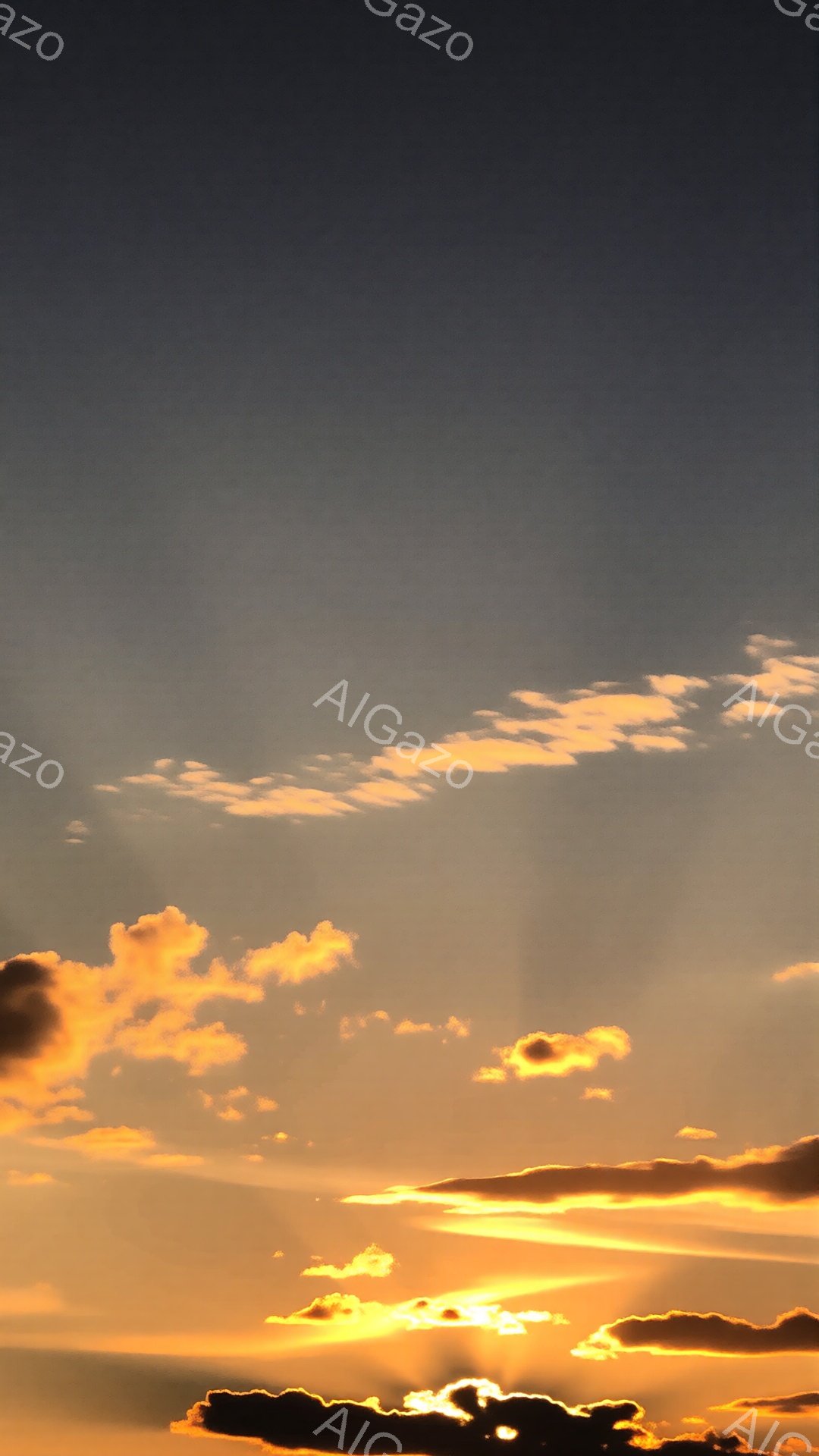 燃えるような夕焼け空が広がっており、オレンジと金色の雲がドラマチックな光景を作り出している。雲は様々な形をしており、まるで絵筆で描かれた水彩画のようだ。太陽は雲の中に隠れており、強い光が雲の縁を照らし、幻想的な雰囲気を醸し出している。