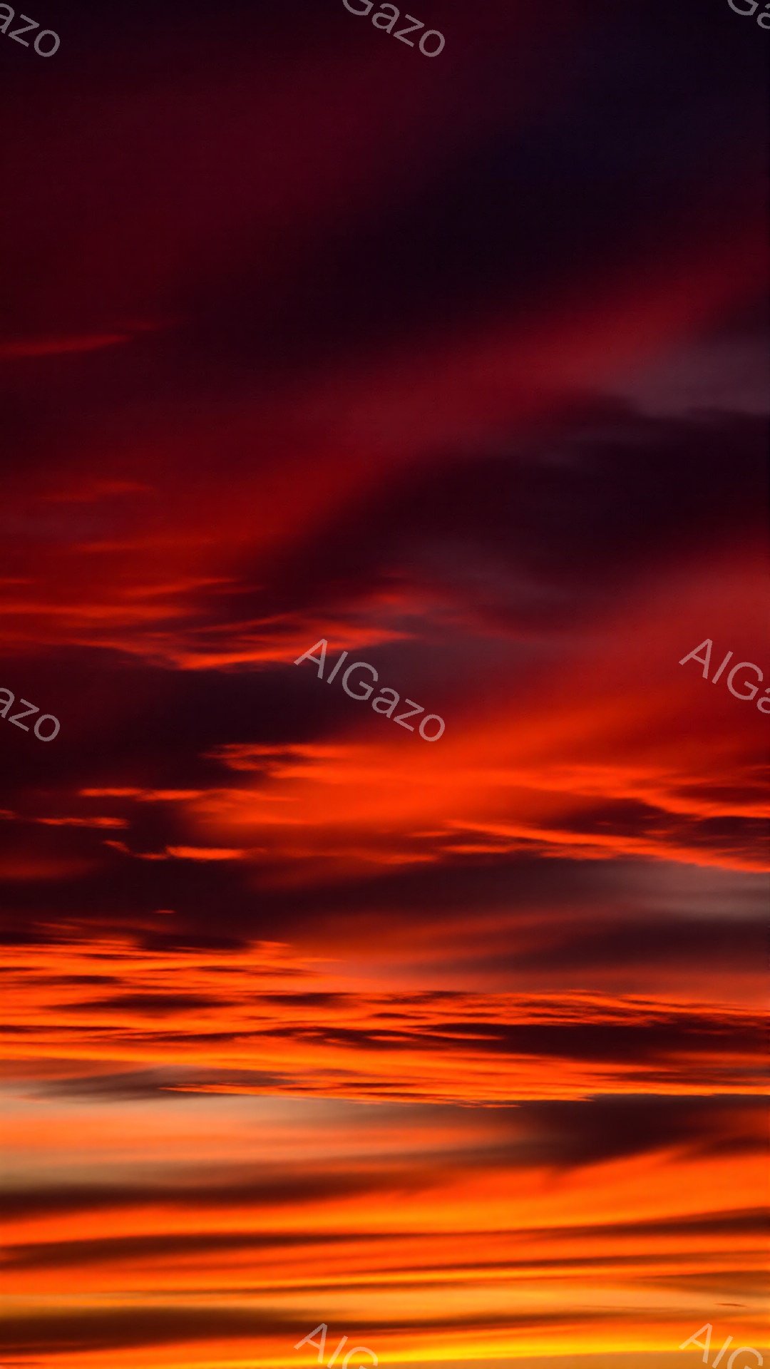 空全体が燃えるような赤とオレンジ色の雲で覆われています。地平線近くは明るい黄色からオレンジ色へとグラデーションを描き、上空へ向かうにつれて深紅や紫の色合いが広がっています。雲の層は水平方向に広がり、まるで絵筆で描かれた壮大な水彩画のようです。
