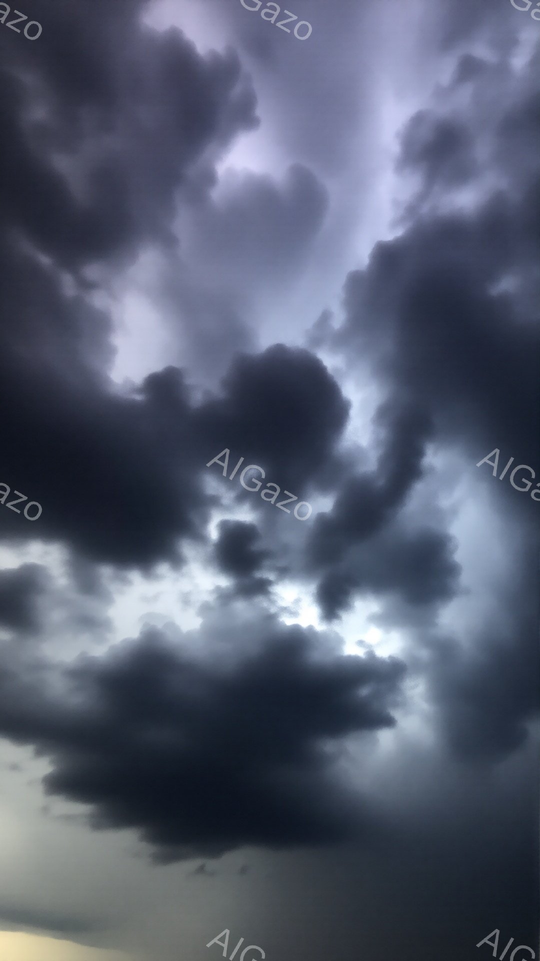 暗い雲が空を覆い、差し込む光がドラマチックなコントラストを生み出している。重厚な雲の層は嵐の前兆を暗示し、重苦しい雰囲気を醸し出している。空の隙間からわずかに見える光は、困難な状況の中の希望の兆しのよ - AI生成フリー素材