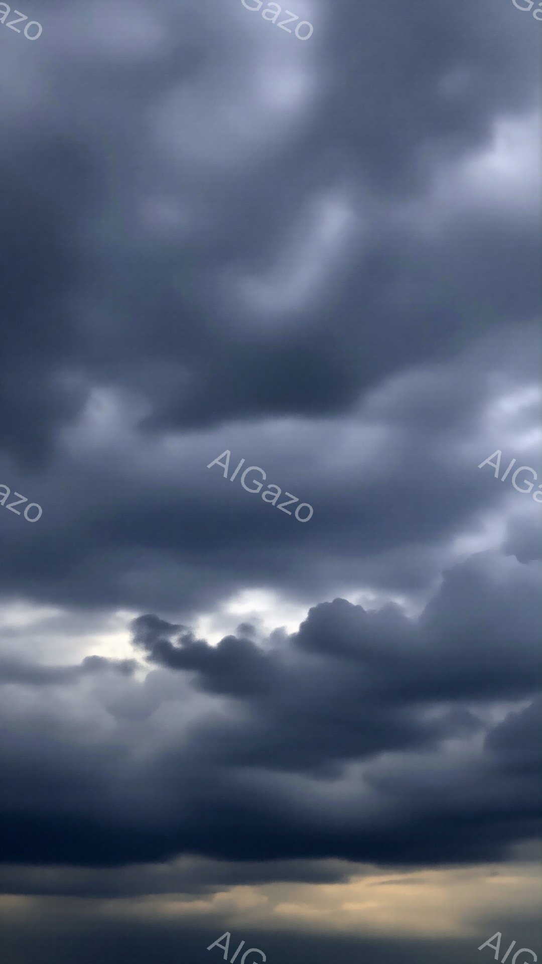 厚い雲が空を覆い、重苦しい雰囲気を醸し出しています。雲の隙間からわずかに光が差し込み、暗闇の中に希望の兆しが見えます。この空は、嵐の前触れか、あるいは嵐が去った後の静けさを表しているのかもしれません。