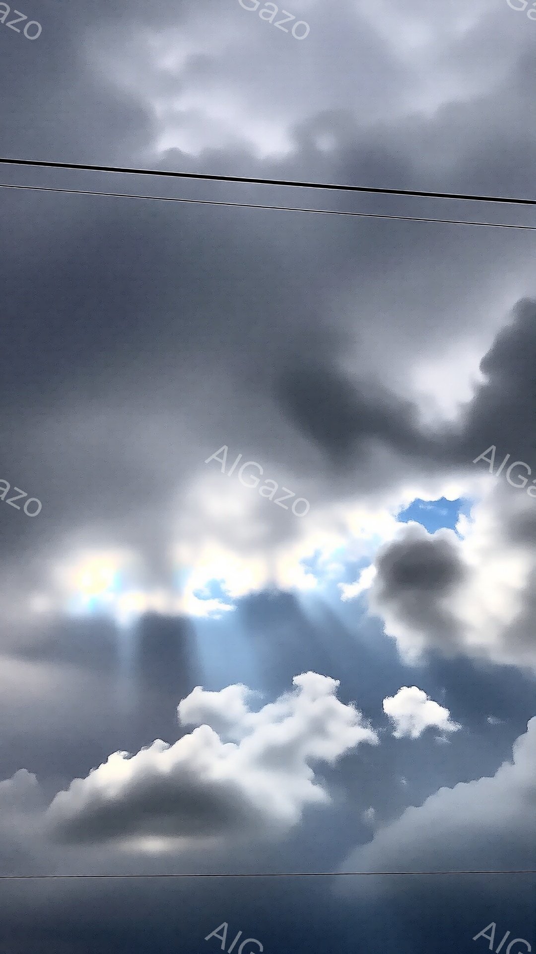 厚い雲に覆われた空に、強い光線が差し込んでいます。雲は白とグレーの濃淡で表現され、光線はまるで神々しい光の柱のように見えます。全体的にドラマチックで、力強い自然のエネルギーを感じさせる光景です。