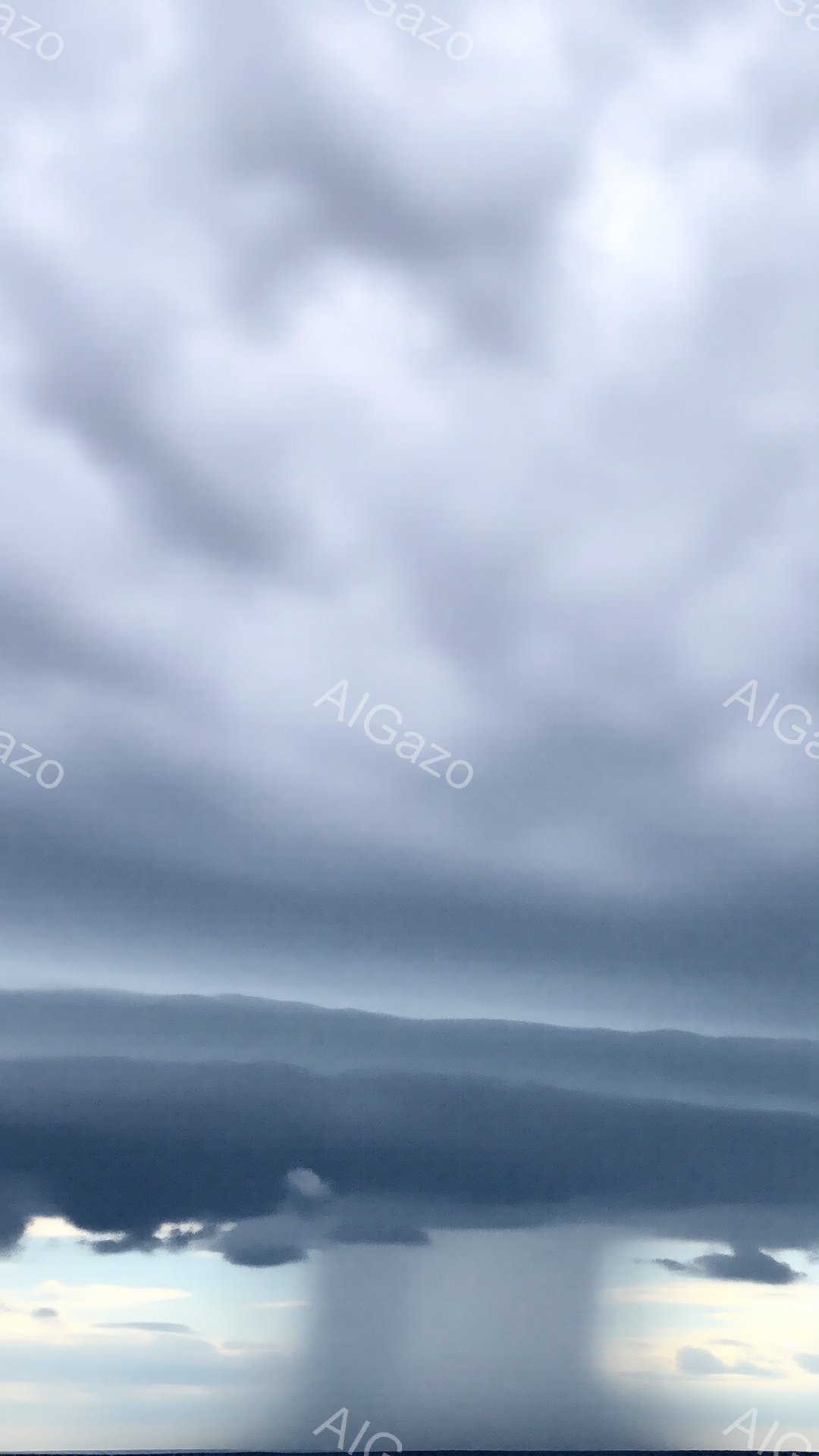 雲が空全体を覆い、重厚な雨雲が特徴的です。層状になった雲はまるで巨大な灰色の波のようで、不穏な嵐の前兆を感じさせます。地平線には薄明るい光が差し込み、雲の暗闇とコントラストをなしています。