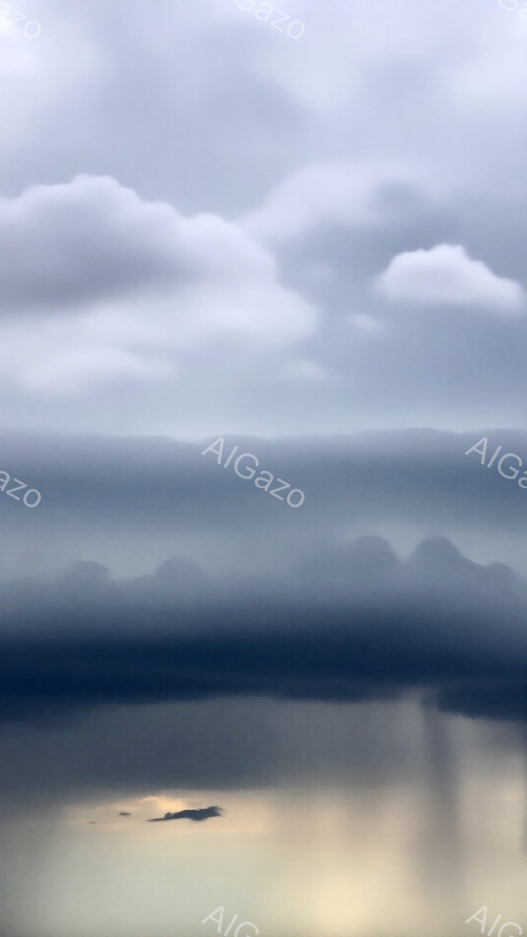 灰色がかった空の下、霧に包まれた山々が連なっている。水面は穏やかで、山の影と夕焼けのようなオレンジ色の光がぼんやりと映り込んでいる。全体的に静寂で神秘的な雰囲気が漂い、まるで水墨画のような印象を与える。