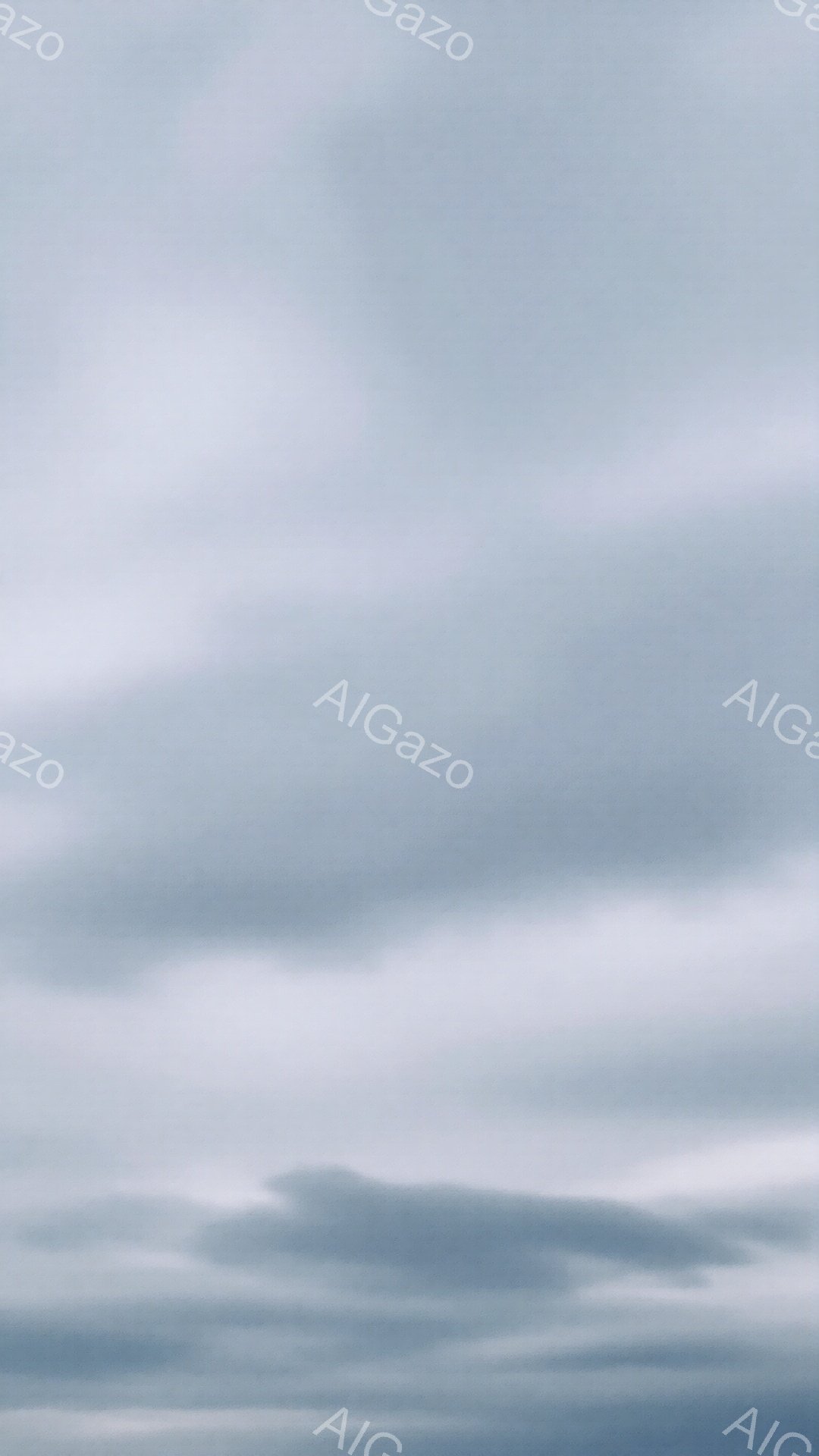 灰色の雲が空一面に広がり、重々しい雰囲気を醸し出しています。雲は様々な形をしており、まるで波のようにうねっています。全体的に、雨が降りそうな、または嵐が近づいてきそうな、憂鬱で陰鬱な空模様です。
