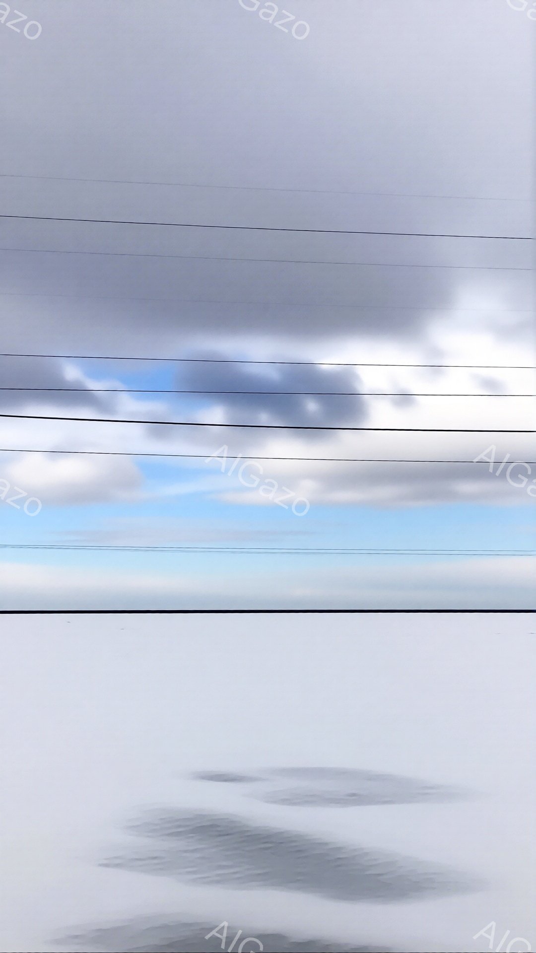 曇り空の下、凍った水面が広がり、その上に足跡がぼんやりと映り込んでいる。電線が空を横切り、水面とのコントラストを際立たせ、全体的に静寂で寒々とした雰囲気を醸し出している。足跡は氷の表面に沈み、冬の寒さを示唆している。