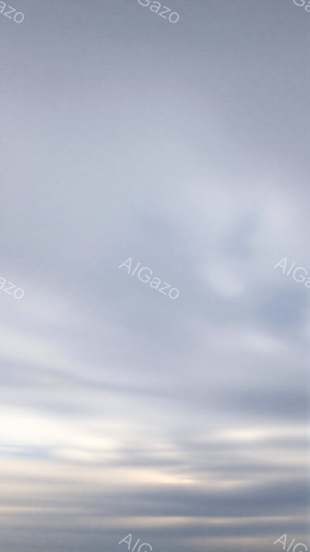 空全体が薄い雲に覆われており、地平線付近にわずかな光が見えます。雲は水平方向に細長く広がり、まるで何層ものベールが空を覆っているかのようです。全体的に穏やかで静寂な雰囲気が漂っており、日の出または日没前の空模様を示唆しています。