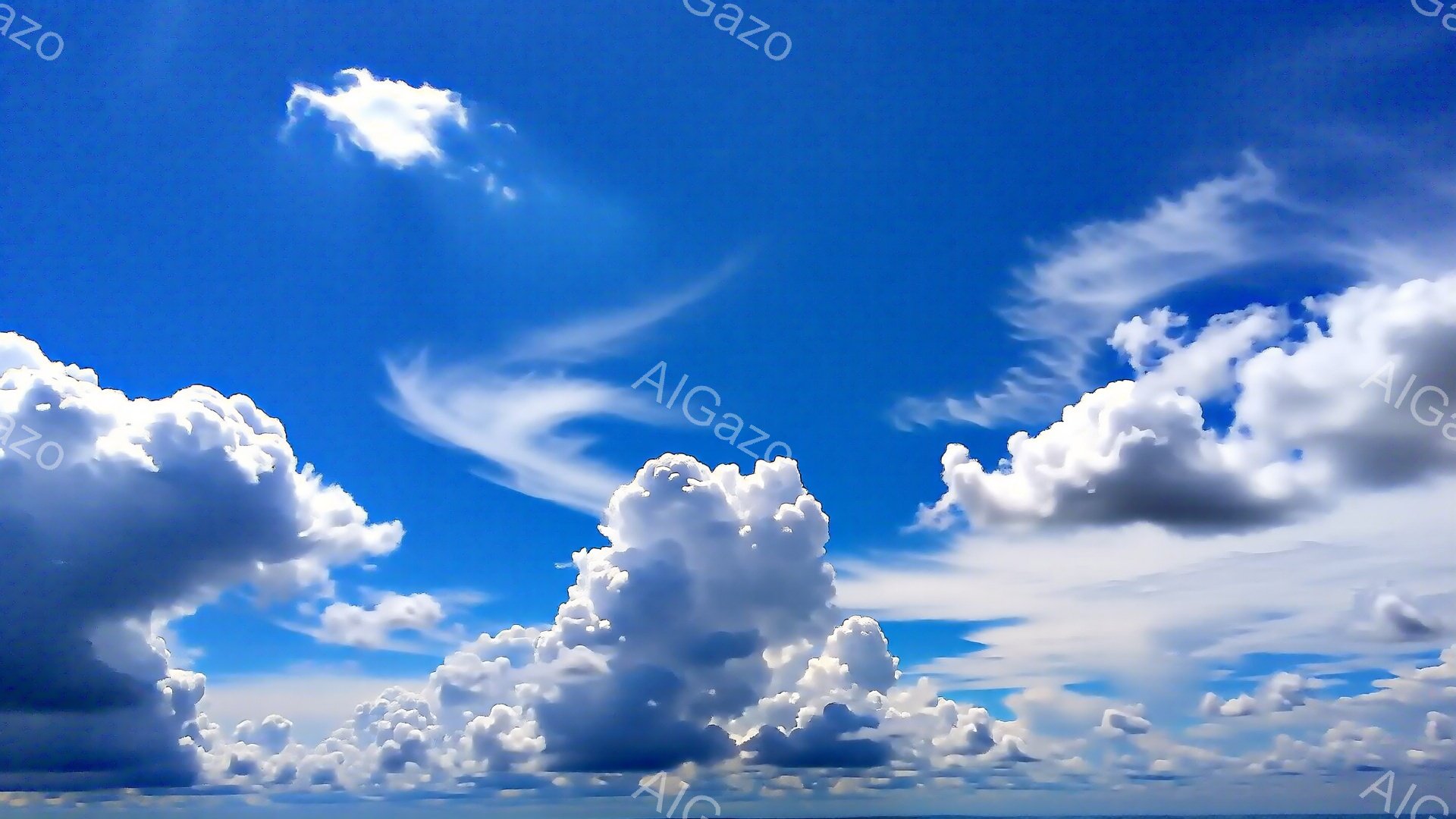 鮮やかな青空に、もくもくと湧き上がる白い雲が広がっている。雲は綿のような形をしており、太陽の光を浴びて輝いている。空の下には水平線が見え、穏やかな夏の日の様子を伝えている。