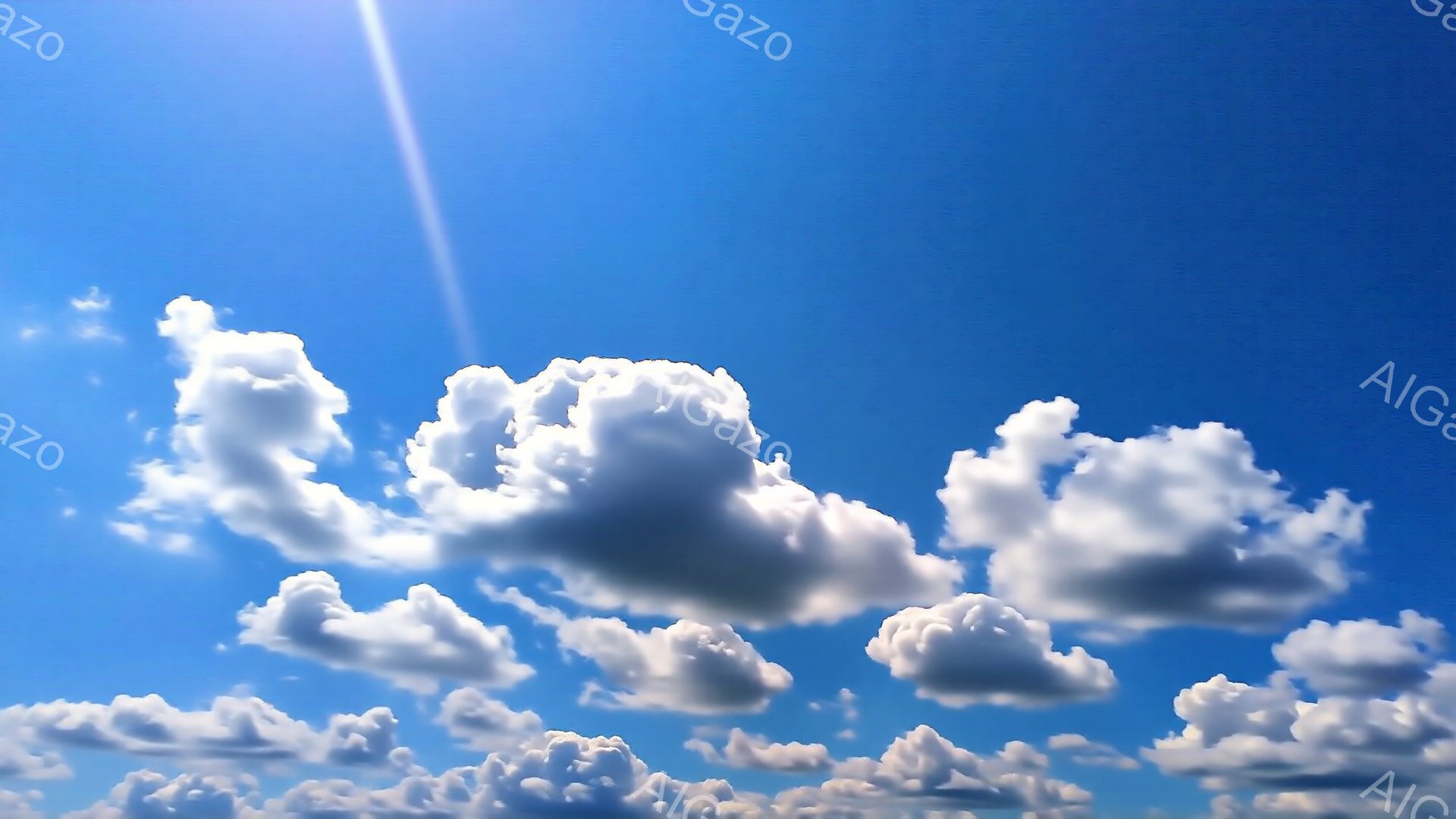 鮮やかな青空に、白いふわふわとした雲が浮かんでいます。太陽光線が雲の合間から差し込み、明るい印象を与えます。穏やかで平和な夏の日の空模様です。