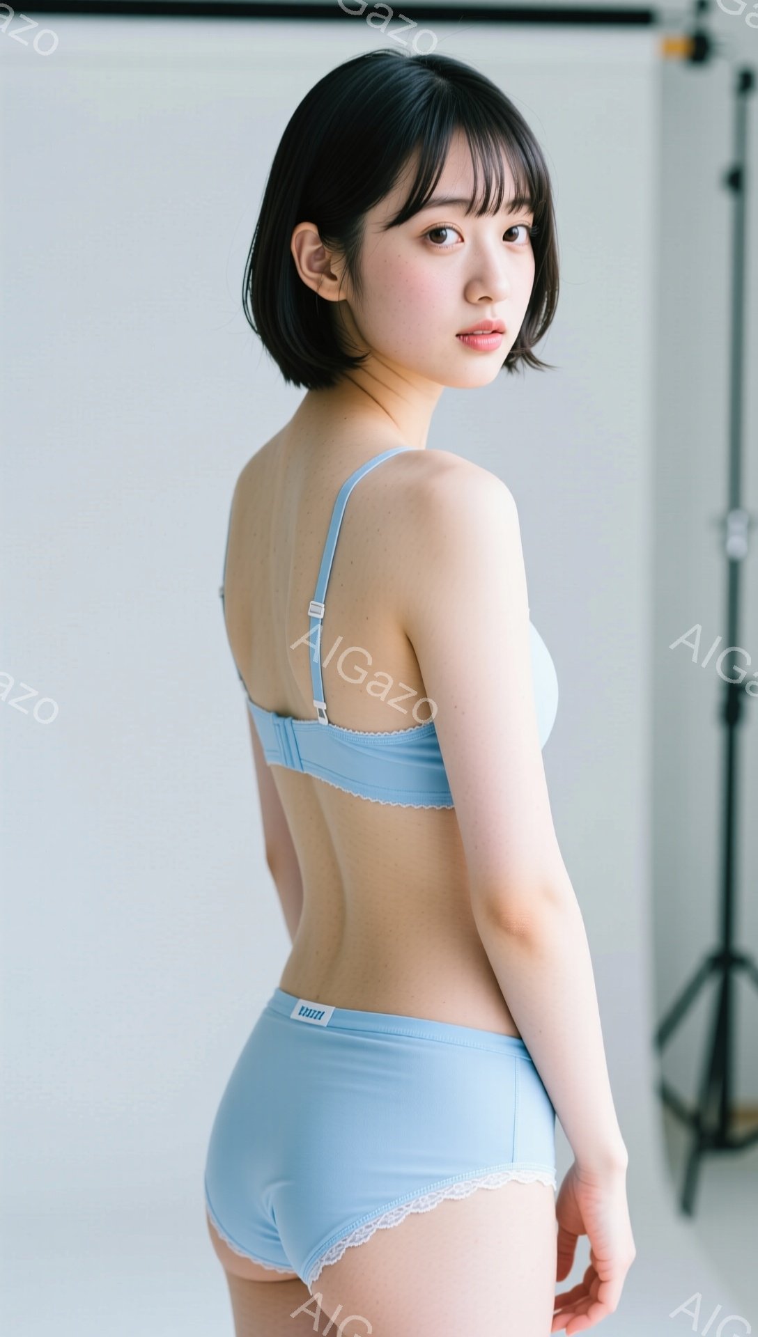 明るいブルーのランジェリーセットを身につけた女性が写っています。彼女はストレートの黒髪で、少し微笑んでおり、正面を向いています。背景は白く、スタジオ撮影であることがわかります。