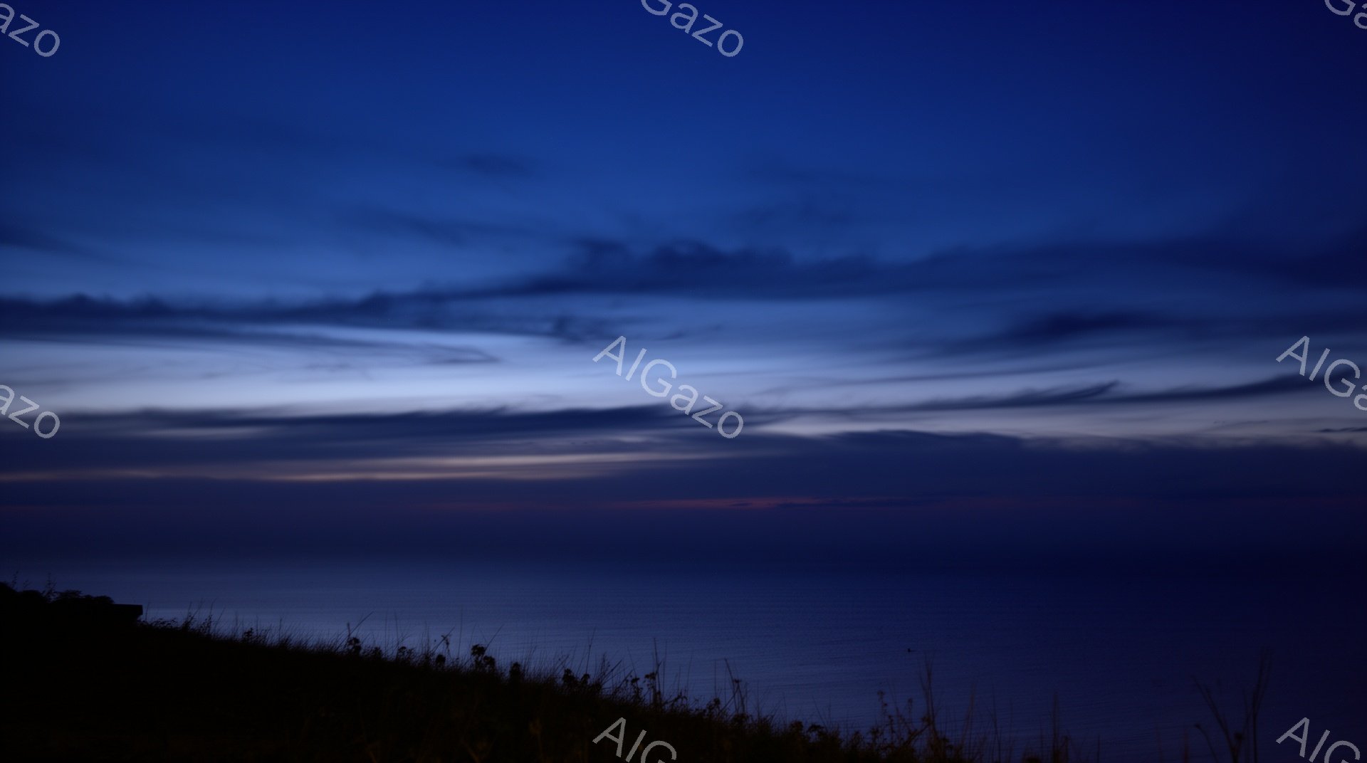 深い青色の空が地平線を覆い、わずかに赤やオレンジ色の光が混じり、夜明けまたは夕暮れを示唆している。前景には、暗いシルエットで草が茂っており、波穏やかな海が広がり、静寂で神秘的な雰囲気を醸し出している。空のグラデーションと海の静けさから、穏やかさと希望を感じさせる風景である。