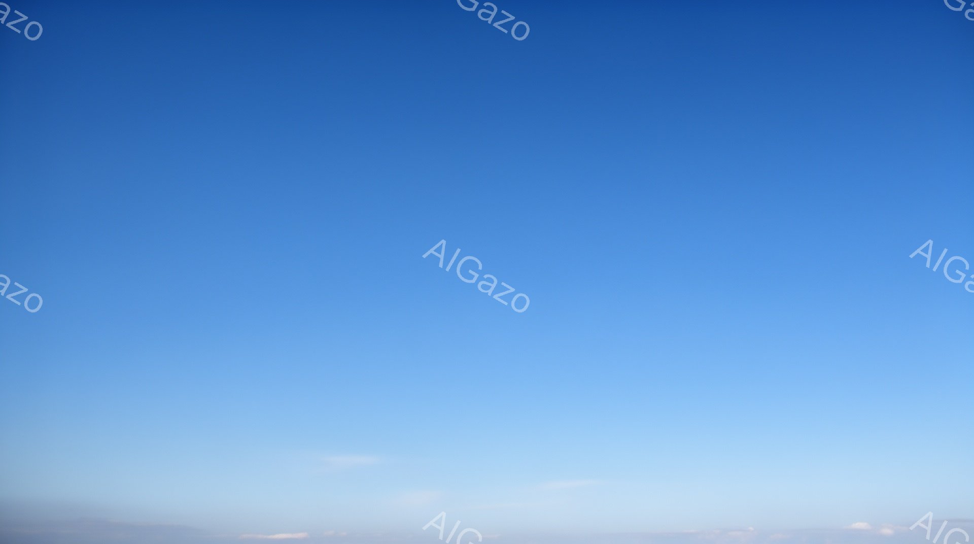 空全体が鮮やかな水色で、地平線付近に薄いピンクと白のグラデーションが見られます。雲はほとんどなく、わずかに地平線近くに白い筋が見える程度です。穏やかで静寂な、晴れた日の空の風景です。