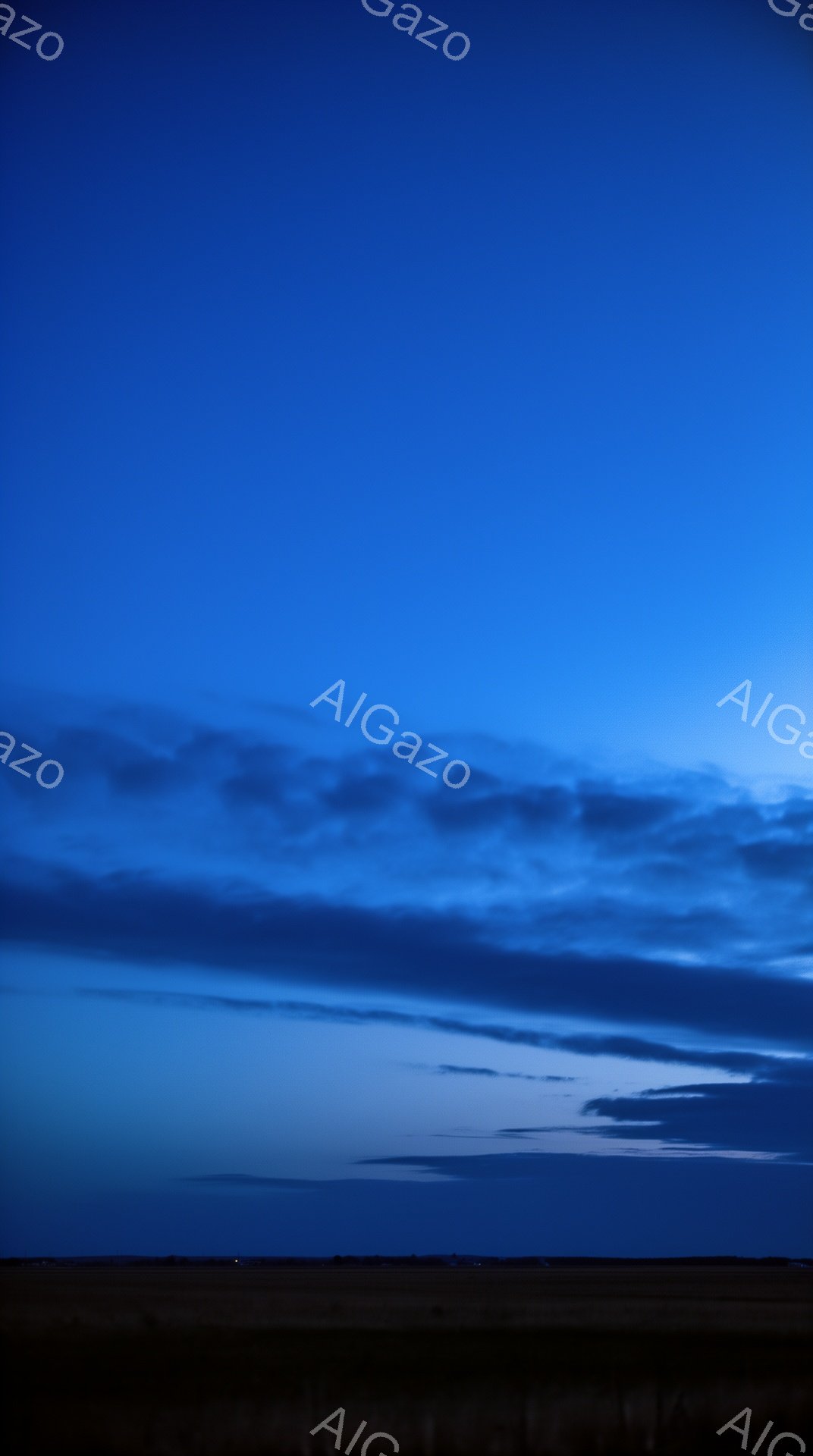 深い青色の空が大部分を占めており、地平線近くに暗い土地が広がっている。空には層状の雲が広がり、薄明かりが雲の端を照らしている。全体的に静かで落ち着いた、夜明け前の静寂が感じられる風景だ。