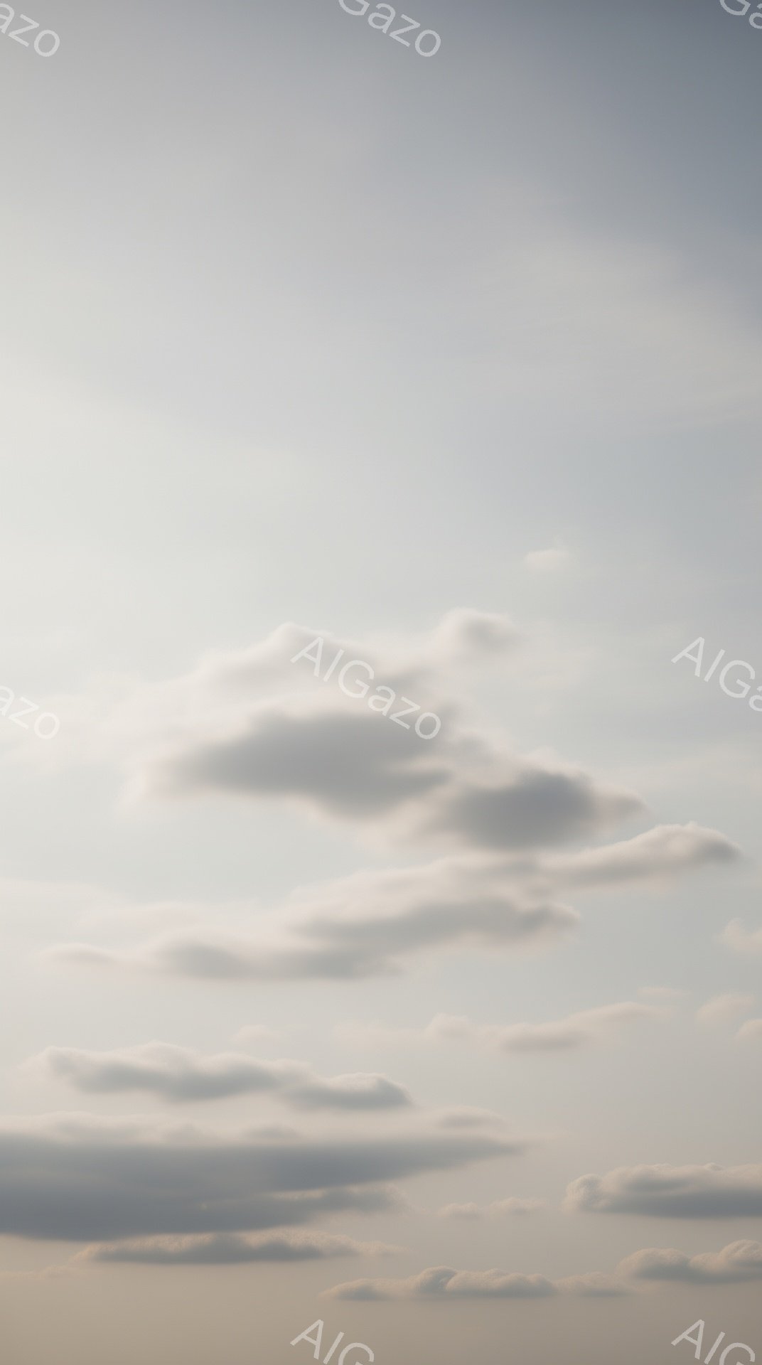 空は薄いグレーと白の雲で覆われており、穏やかで少し憂鬱な雰囲気を醸し出しています。雲は様々な形をしており、まるで綿菓子のようです。地平線付近は薄いオレンジ色に染まっており、夕暮れ時または朝焼けの情景を思わせます。