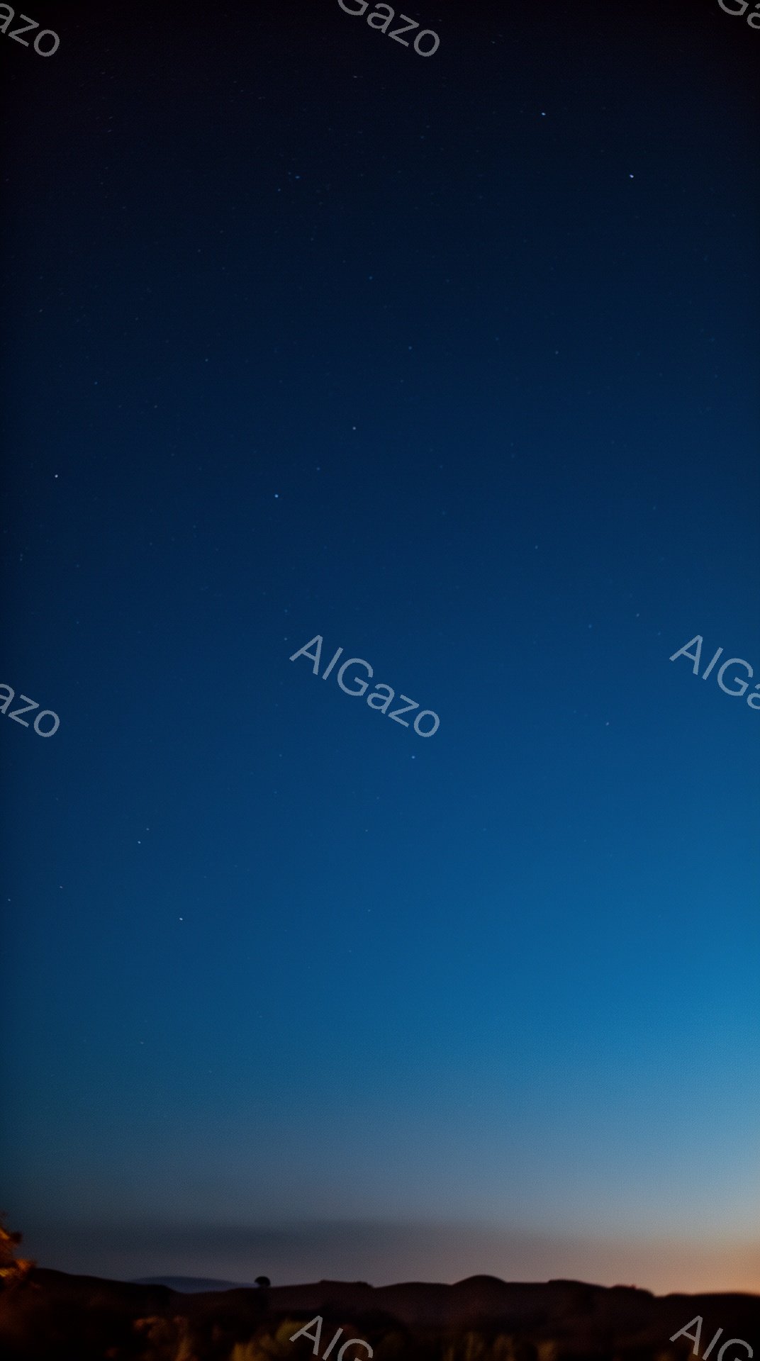 深い青色の夜空に星が散りばめられており、地平線付近は薄いオレンジ色から青色へとグラデーションを描いている。地平線上には、暗いシルエットの山並みが連なり、右下にわずかに植物が見える。静寂で神秘的な大自然の夜の雰囲気が漂っている。