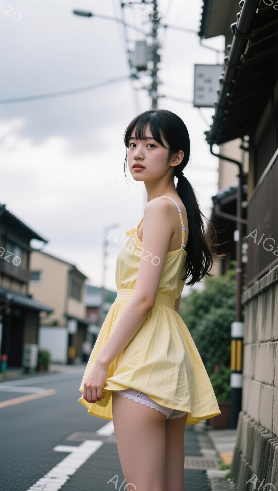 若い女性が黄色いキャミソールワンピースを着て、アスファルトの道端に立っています。彼女は黒髪をポニーテールにし、少し微笑んでいます。背景には、日本の古い街並みと曇り空が見え、全体的にノスタルジックで穏や - AI生成フリー素材