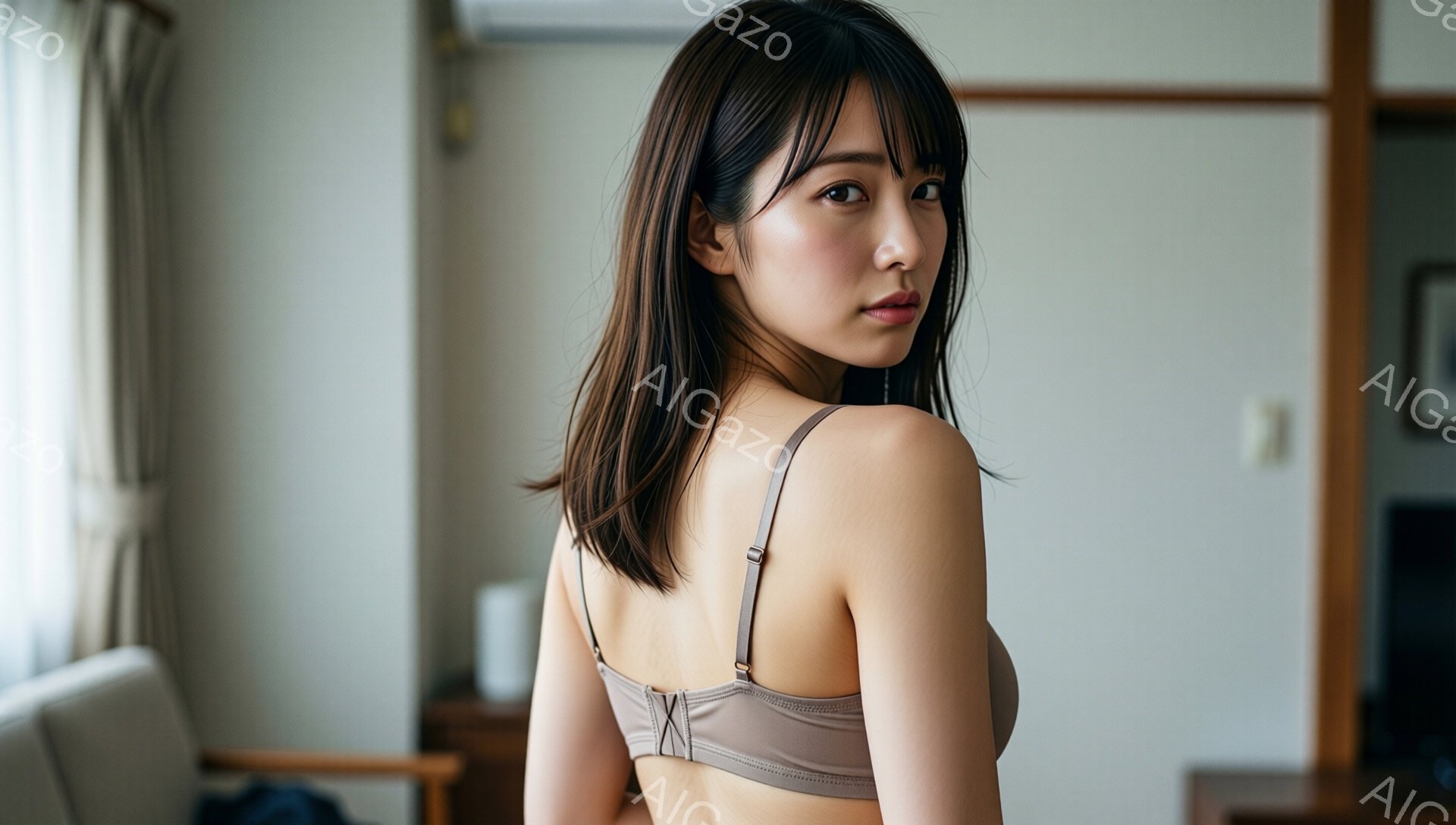 長い茶色の髪は肩にかかる程度にカットされ、前髪が眉毛にかかっています。女性はベージュ色のキャミソールを着ており、背中を少し見せています。背景には木製の家具と壁があり、室内である様子がわかります。