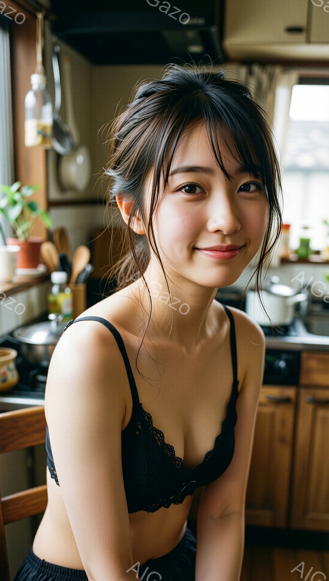 画像には、キッチンで椅子に座っている若い女性が写っています。彼女は黒いレースのブラレットと下着を身につけており、髪は無造作にまとめられています。微笑みを浮かべた表情で、カメラの方を優しく見つめており、背景には調理器具や木製のキャビネットが見えます。