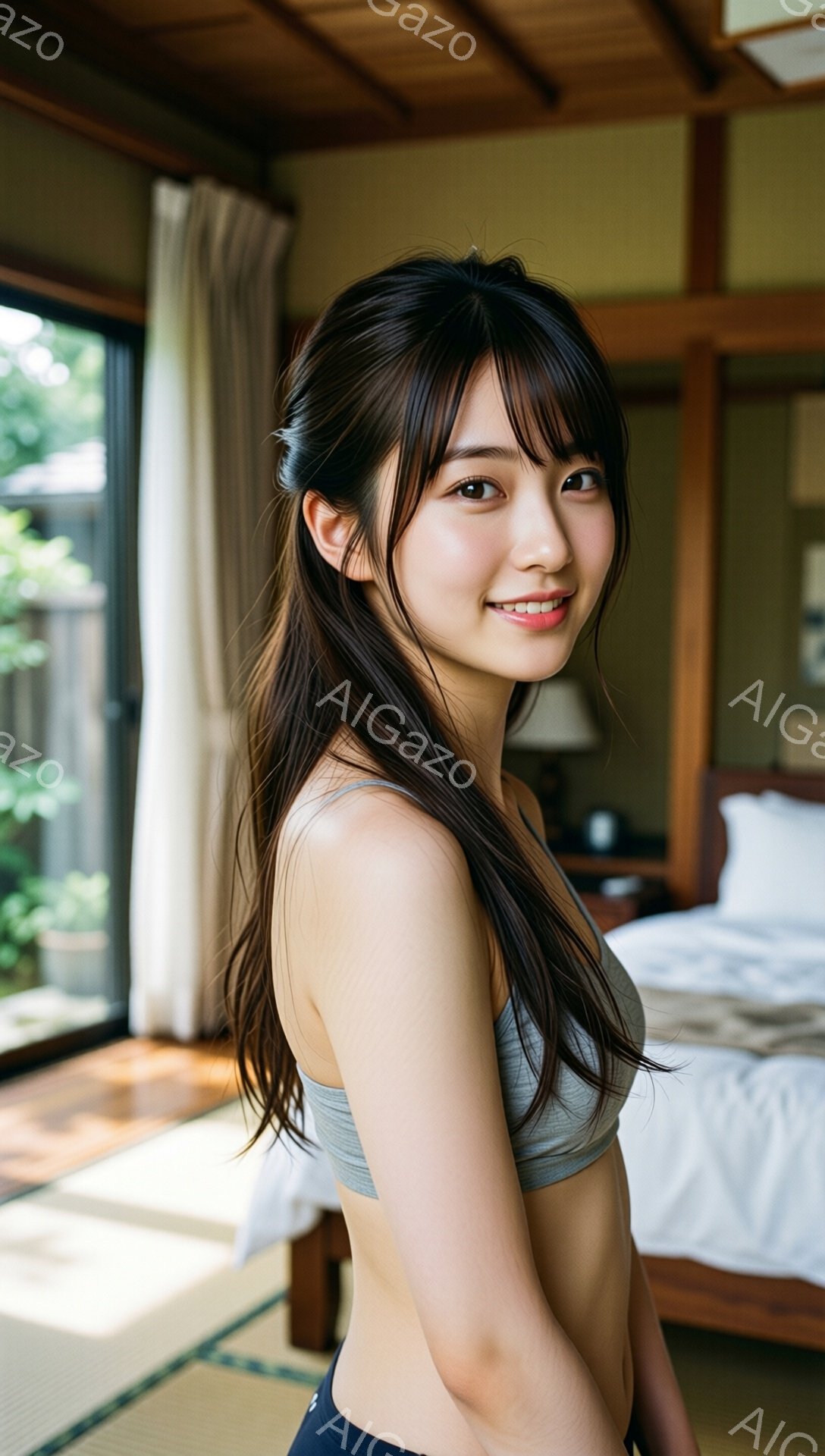 長い黒髪を後ろに流し、グレーのスポーツブラと紺色のボトムスを着用した若い女性が写っています。彼女は微笑んでおり、リラックスした姿勢でカメラを見ています。背景には畳敷きの部屋と庭が見え、明るい日差しが差し込んで穏やかな雰囲気を醸し出しています。