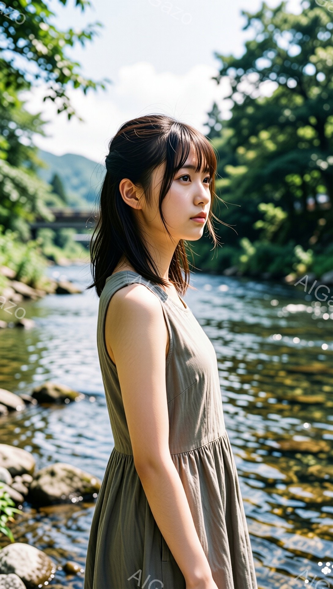 若い女性が、浅い川のそばに立っている。彼女はオリーブ色のゆったりとしたワンピースを着ており、前髪を下ろしたダークブラウンの髪は肩にかかっている。表情は穏やかで、どこか遠くを見つめているように見える。